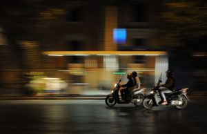 2 scooters speeding on a city road at night